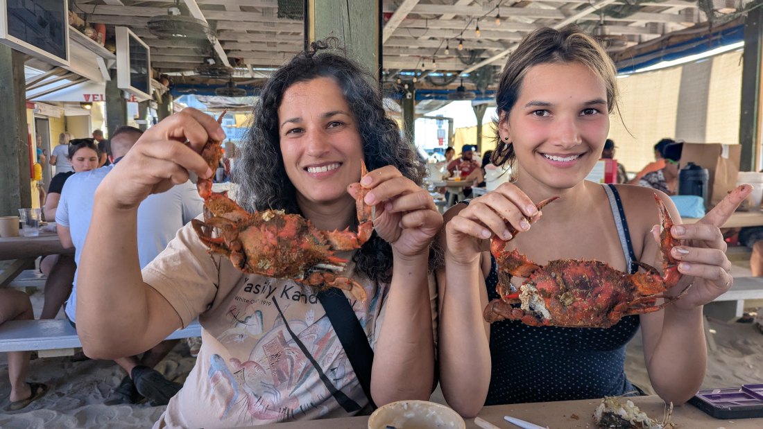 The same mother and her daughter, 17 years later, each holding up a steamed crab at On the Bay Seafood